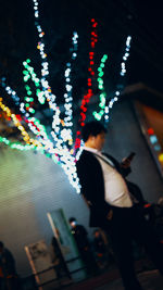 Reflection of people on illuminated lights in city at night