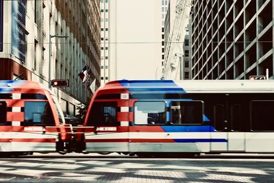 Train on street by buildings in city
