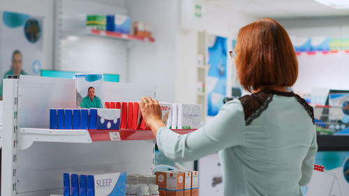 Rear view of woman using mobile phone in store