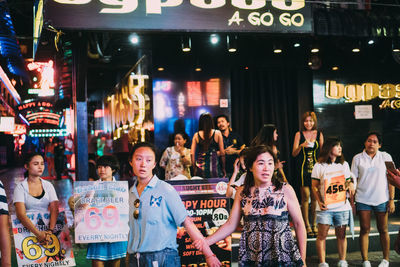 Group of people standing in city at night