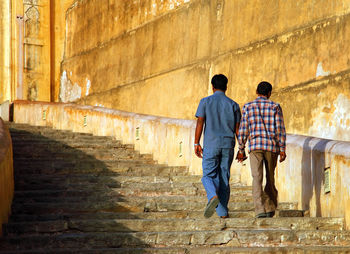 Rear view of men moving up steps at amer fort