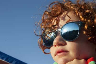 Portrait of woman with sunglasses against blue sky