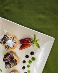 High angle view of profiteroles garnished with strawberry in tray on table
