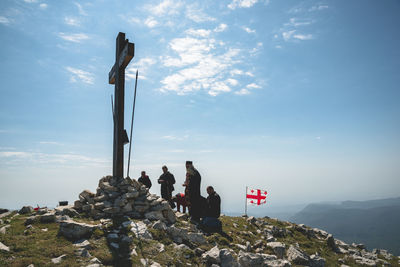People by cross on mountain