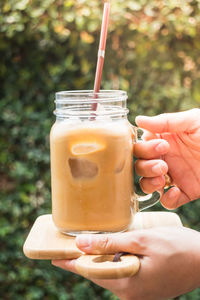 Cropped hands of man holding drink on cutting board