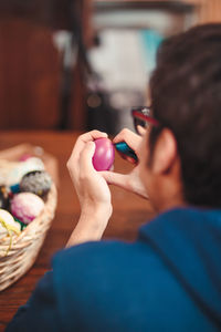 Close-up of man decorating easter egg at home