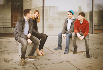 Full length of young couple sitting outdoors