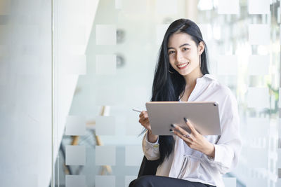 Portrait of smiling young businesswoman holding digital tablet