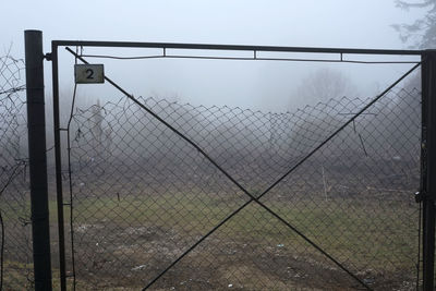 Barbed wire fence on field against sky