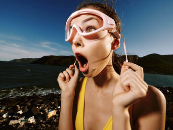 Portrait of young woman applying make-up against sky