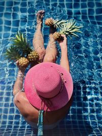 High angle view of girl and woman with pineapple sitting in swimming pool