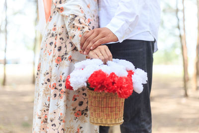 Midsection of couple with bouquet standing in park
