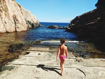 Rear view of girl walking by sea