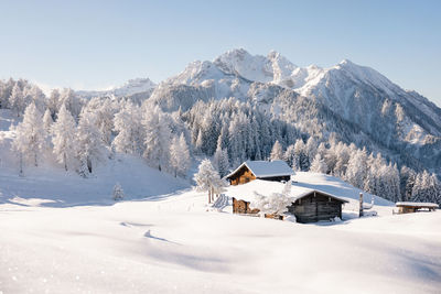 Picturesque winter scene with traditional alpine chalet and snowy mountains
