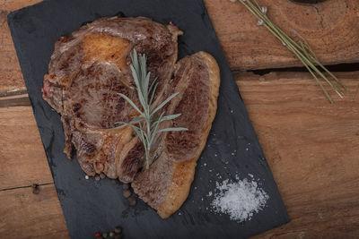Grilled beef steaks with spices on wooden cutting board.