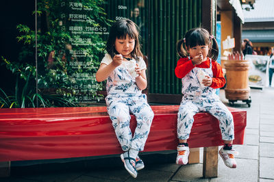 Full length of a smiling girl sitting outdoors