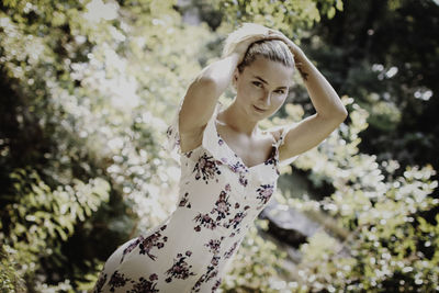 Young woman standing by tree against blurred background