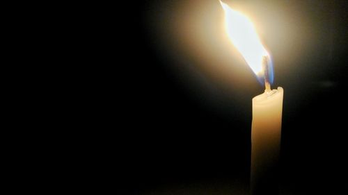 Close-up of lit candle in dark room