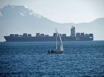 Sailboat in sea against mountains and sky