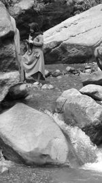 Rear view of couple sitting on rock