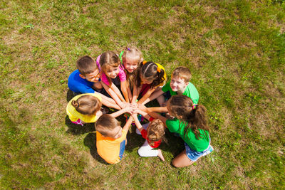 High angle view of kids stacking hands in park