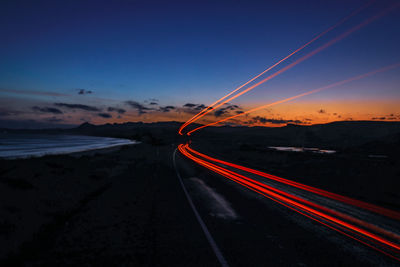 Light trails on road against sky during sunset