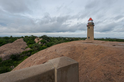 Lighthouse amidst buildings against sky