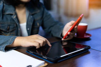 Midsection of woman using mobile phone on table