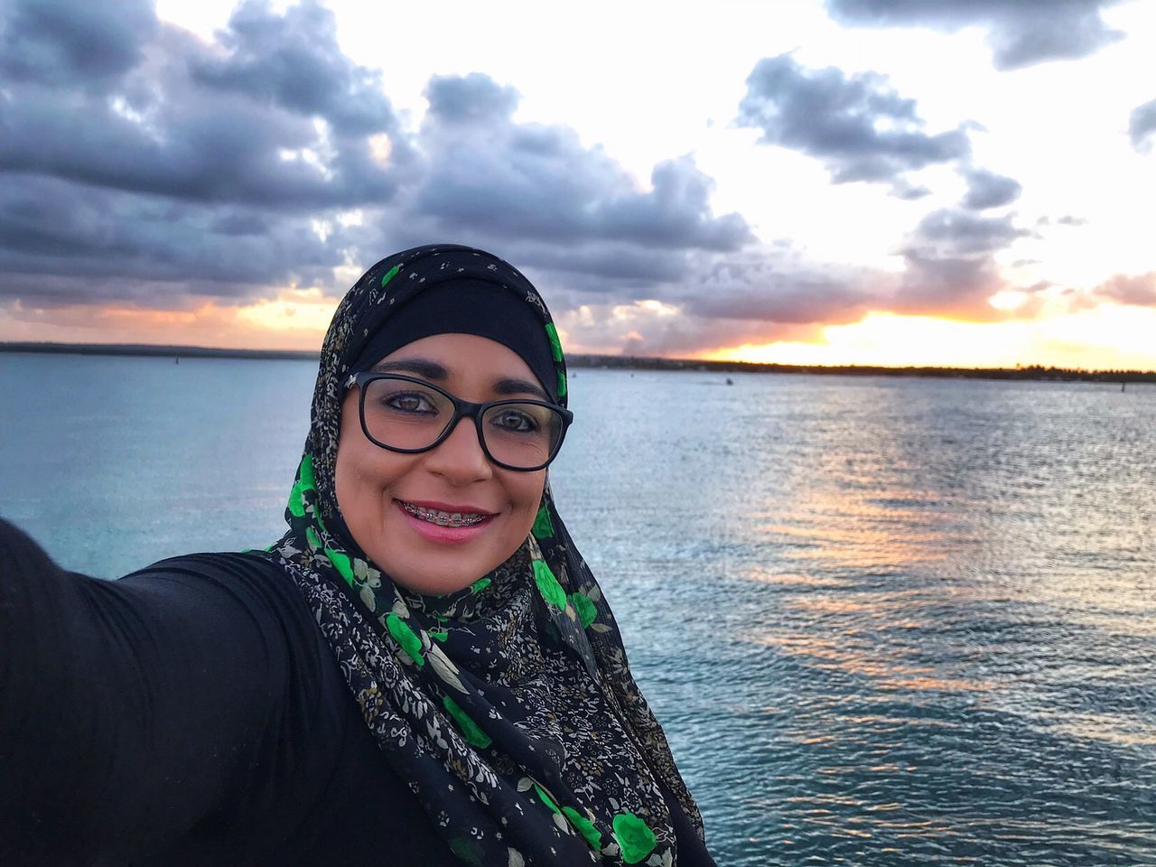 PORTRAIT OF SMILING YOUNG WOMAN AGAINST SEA