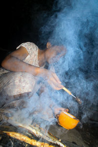 Woman preparing food on grill in darkroom