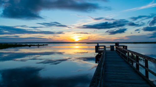 Pier over lake against sky during sunset