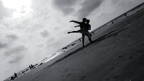 Low angle view of silhouette man jumping against sky