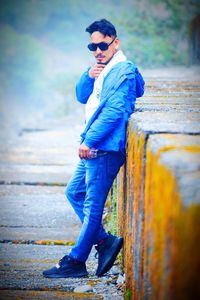 Full length of young man wearing sunglasses standing on footpath