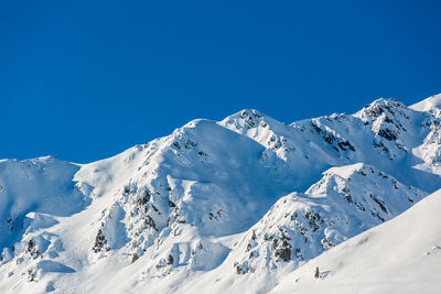 Scenic view of snowcapped mountains against clear blue sky