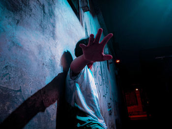 Midsection of man standing by illuminated wall at night