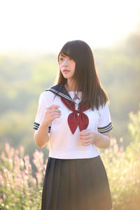 Beautiful young woman wearing uniform while standing on land