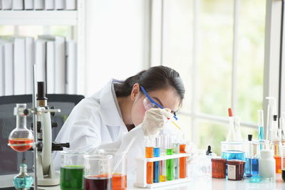 Scientist working while sitting at table by window in laboratory