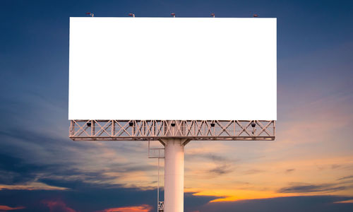 Low angle view of signboard against sky during sunset