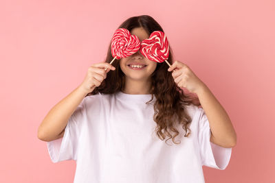 Portrait of young woman against pink background