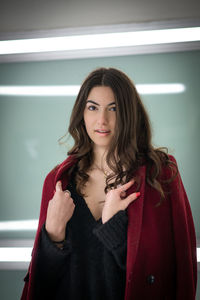 Portrait of beautiful young woman standing against wall