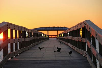 People on bridge against clear sky during sunset