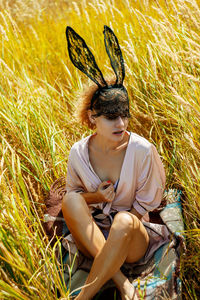 Fashion woman in rabbit mask in green field