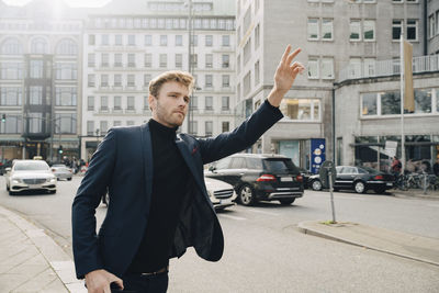 Male entrepreneur looking away while hailing for ride in city