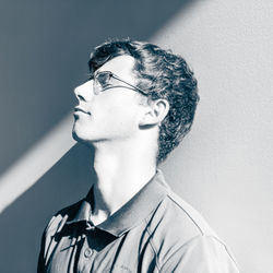 Close-up of young man looking away against wall