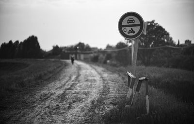 Road sign on field against sky