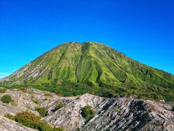 Scenic view of volcanic mountain against blue sky
