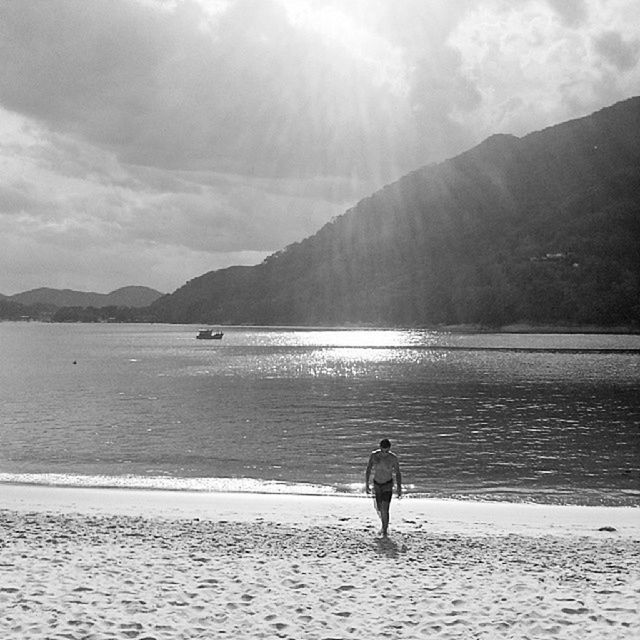 water, leisure activity, lifestyles, sea, sky, full length, mountain, scenics, rear view, tranquil scene, beauty in nature, vacations, beach, nature, men, tranquility, sunlight, cloud - sky