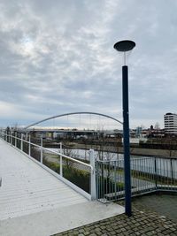 Street light by footpath against sky