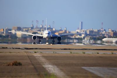 Airplane flying in city against sky