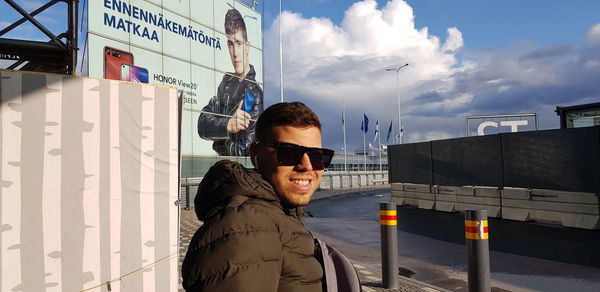 Portrait of smiling man standing on bus against sky